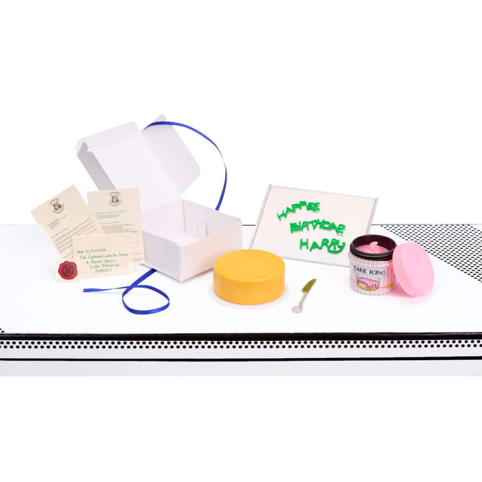 Collection of party supplies including a cake, and decorations on a white surface.