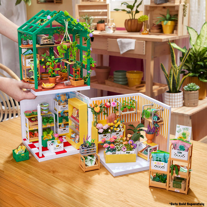 Miniature greenhouse model with plants on a wooden surface
